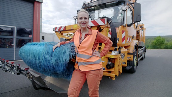 Henriette steht in Warnweste an einem Fahrzeug.