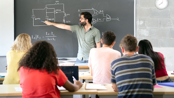 Ein Professor erklärt den Unterrichtsstoff, während die Schüler aufmerksam zuhören und in einem Klassenzimmer sitzen.