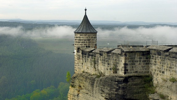 Mauer der Festung Königsstein mit Türmchen - darunter Nebel im Elbtal