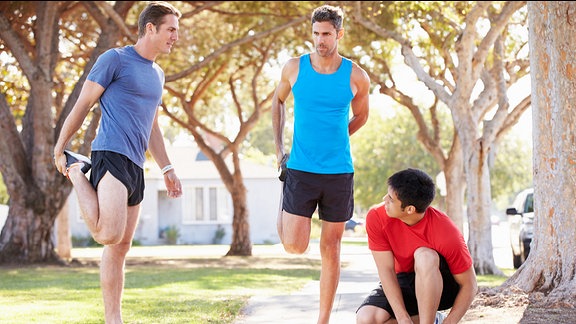 Drei Männer machen Dehnungsübungen vorm Joggen.