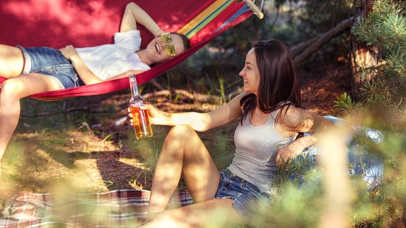 Eine junge Frau mit Hut sitzt in der Sonne