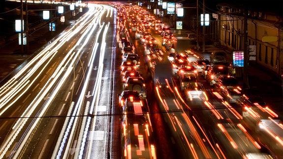 Lichtspuren von fahrenden Autos auf einer nächtlichen Straße.