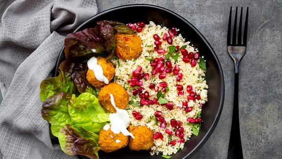 Schale Falafel mit Kopfsalat, Joghurt, Granatapfelkernen, Petersilie, Minze und Tabbouleh-Salat.