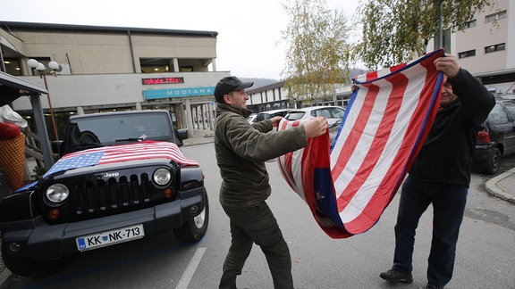 Zwei Männer falten eine Flagge zusammen.