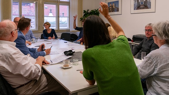 Menschen sitzen an einem Tisch 