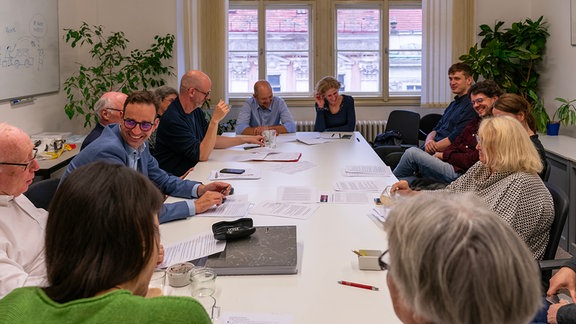 Menschen sitzen an einem Tisch 