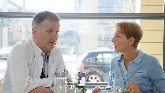 Pia Heilmann (Hendrikje Fitz) möchte von ihrem Mann Dr. Roland Heilmann (Thomas Rühmann) wissen, wie lange er am Nachmittag im OP stehen wird.