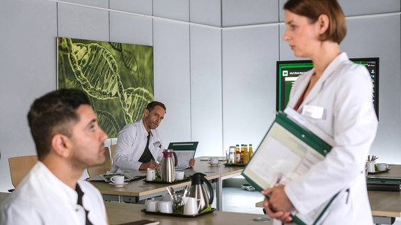 Drei Personen im weißen Kittel in einem Büro