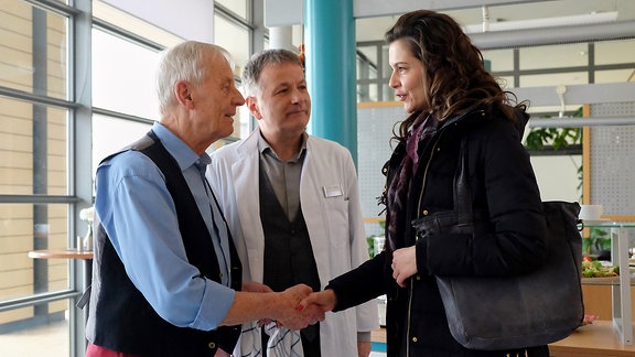 Bei einem Überraschungsbesuch am Vorabend hat Roland Heilmann (Thomas Rühmann, mi.) Martin Steins Freundin Sophia Müller (Susan Hoecke, re.) kennengelernt. Als diese in der Sachsenklinik zu einer Nachuntersuchung auftaucht, stellt Roland sie kurzerhand Martins Vater Otto (Rolf Becker, li.) vor. Dass das mit Sophia Martins Privatsache ist und er damit nicht hausieren geht und das auch nicht vorhat, interessiert weder Roland noch Otto.