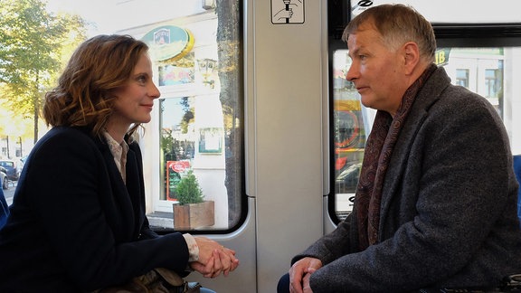 Roland Heilmann (Thomas Rühmann) seitzt mit einer Frau (Julia Jäger) in der Bahn.