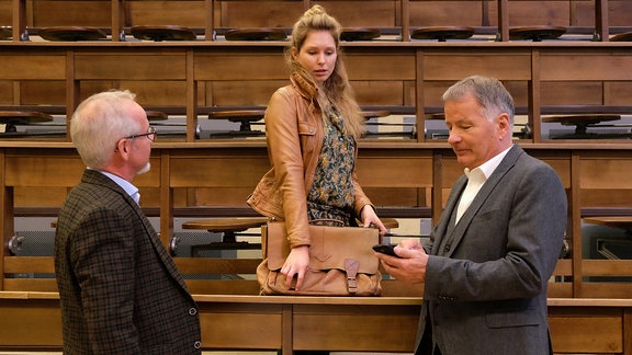 Dr. Roland Heilmann (Thomas Rühmann, re.) im Hörsaal mit einer Studentin  (Stephanie Krogmann, mi.) Probleme mit ihrem rechten Arm hat und Professor Robert Kessler (Marcus Calvin, li.).