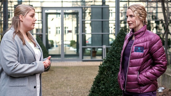 Schwester Miriam Schneider (Christina Petersen, li.) steht mit Dr. Julia Berger (Mirka Pigulla, re.) vor der Sachsenklinik. 