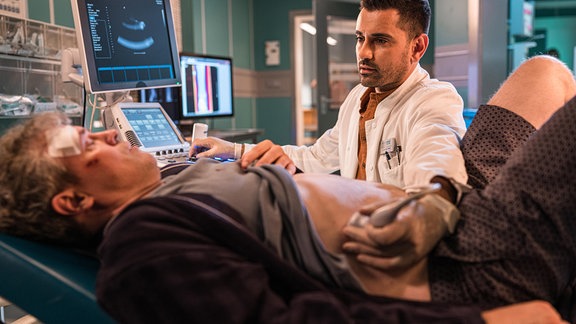 Dr. Demir untersucht den Bauch des Patienten in der Klinik mit einem Ultraschallgerät.