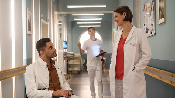 Dr. Ilay Demir und Dr. Maria Weber unterhalten sich in einem Gang in der Sachsenklinik.