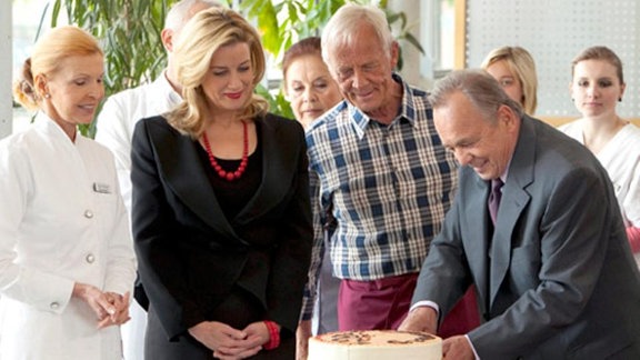 Als Prof. Simoni einen Kuchen anschneiden will, zittert seine Hand.