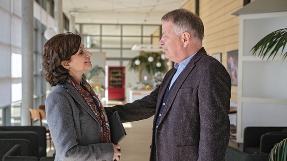 Dr. Roland Heilmann (Thomas Rühmann) begrüßt Prof. Dr. Karin Patzelt (Marijam Agischewa). 