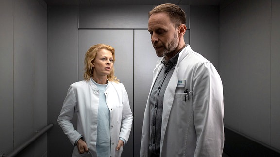 Dr. Ina Schulte (Isabell Gerschke) und Dr. Kai Hoffmann (Julian Weigend) nebeneinander im Aufzug.