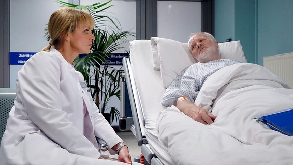 Dr. Lea Peters (Anja Nejarri) sitzt am Krankenbett von Hilger Derbeck (Peter Franke).