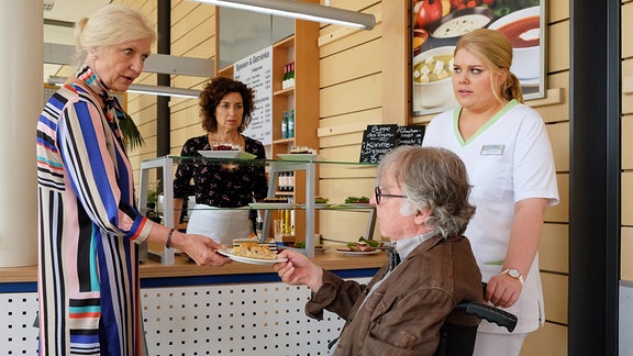 Heinz Rudolph will gerade ein Stück Kuchen von Linda Schneider (Isabel Varell, 2.v.li.) genießen, als Schwester Miriam (Christina Petersen, re.) ihm das verbietet