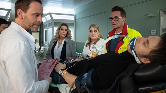 Notarzt Dr. Lorenz (Markus Neumann, 2.v.li.) mit dem Patienten Tobias Rauch (Guido Broscheit, li.) und Sarah Marquardt (Alexa Maria Surholt, 2.v.re.) sowie Dr. Kai Hoffmann (Julian Weigend, re.) und Schwester Miriam (Christina Petersen, mi.) 