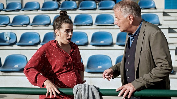 Roland Heilmann (Thomas Rühmann) mit der hochschwangeren Nadine Heller (Julia-Maria Kühler) auf dem Sportplatz.