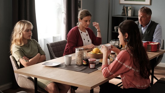 Die Familien Heilmann und Brückner sitzen zusammen am Tisch.