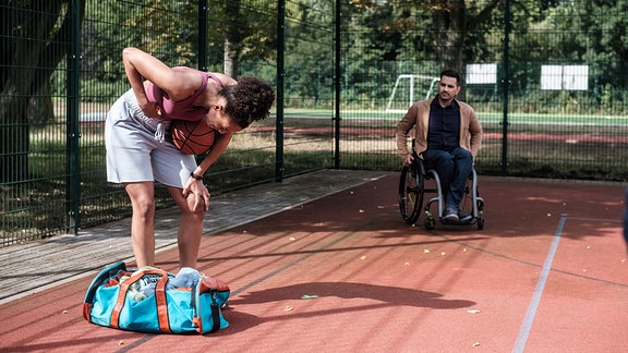 Eine Frau krümmt sich auf dem Basketballfeld vor Schmerz