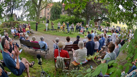 Menschen hören bei einem Open Air Konzert zu. 