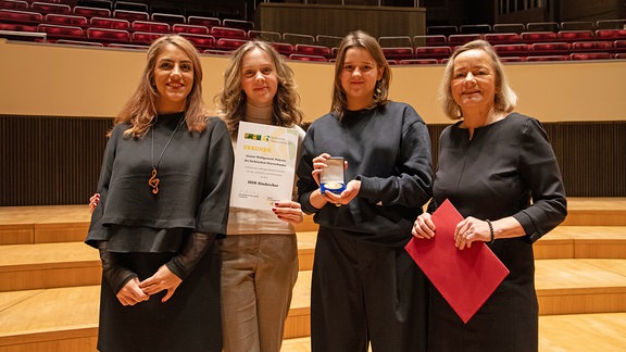 Vier Frauen auf der Bühne des Leipziger Gewandhauses: MDR-Kinderchor-Managerin Shafagh Aghaei, zwei Chormitglieder, Journalistin Petra Mewes (v. l. n. r.).