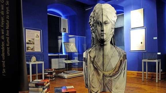 Blau gestrichener Ausstellungsraum der Novalisgedenkstätte im Schloss Oberwiederstedt in Wiederstedt, zu sehen sind Vitrinen und andere Ausstellungsstücke.