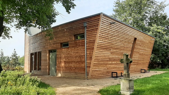 Eine holzverkleidetes Gebäude, das optisch an eine Arche erinnert.