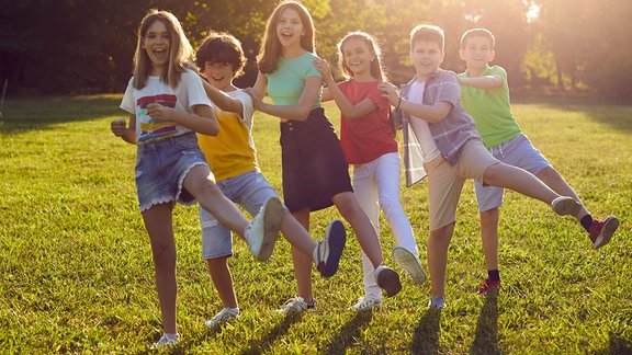 Kinder halten sich gegenseitig an den Schultern und lachen