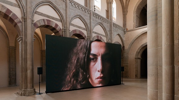 Blick in die Ausstellung "Splitter" im Kunstmuseum Magdeburg: das große Porträt einer jungen Frau steht in der Mitte der Klosterkirche