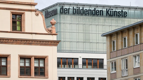 Das Museum der bildenden Künste ragt als Glasbau hinter anderen, historischen Gebäuden empor. Ober steht an der Fassade der Schriftzug Museum der bildenden Künste.