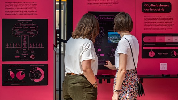 Zwei Frauen stehen vor einer roten Ausstellungswand