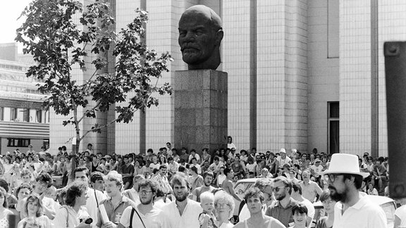 Teilnehmende des Evangelischen Kirchentags im Juli 1989 vor Leninbüste in Leipzig.