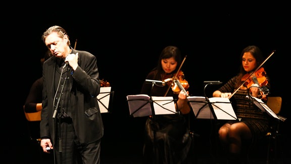 Mehrere Musiker auf einer Bühne mit Instrumenten in der Hand