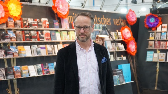 Roman Pliske, ein Mann vor einem Bücherstand