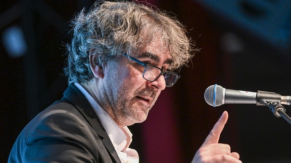 Deniz Yücel, Journalist und Co-Sprecher der Autorenvereinigung Pen-Berlin, steht mit erhobenem Zeigefinger vor einem Mikrofon.