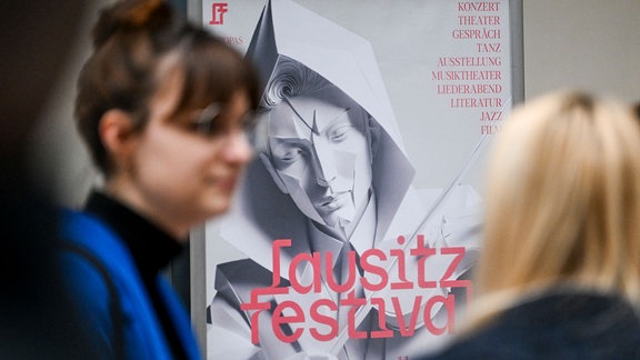 Frau Frauen stehen vor einem Plakat mit der Aufschrift "Lausitz Festival"