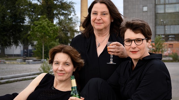 Annett Gröschner, Peggy Mädler und Wenke Seemann posieren mit Sekt für ein Foto.