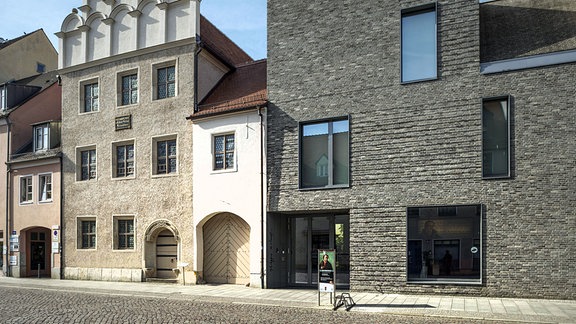 Ein sehr altes Haus und rechts daneben ein Neubau.