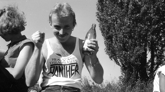 Ein erfreuter junger Mann mit einer Flasche in der Hand