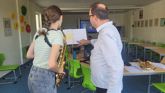 Ein Mann und eine junge Frau mit Saxophon vor einem Notenständer