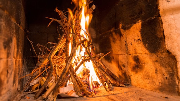 Ein Holzscheit brennt in einem Kamin.