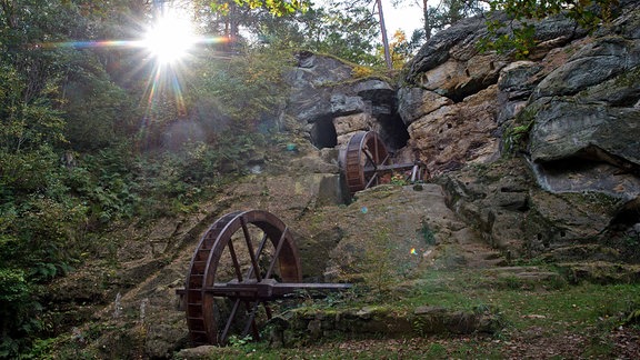 Mitten im Wald befinden sich die historischen Mühlräder der Regensteinmühle; zu sehen sind zwei Holzräder