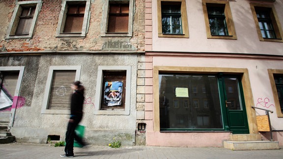 Eine Frau geht an leerstehenden Häusern in Dresden vorüber.