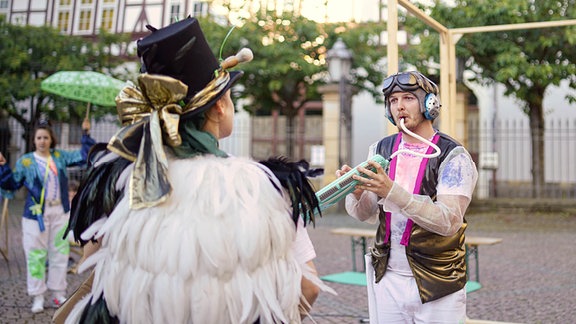 Eine Gruppe Schauspielerinnen und Schauspieler in fantastischen Kostümen spielt auf einer Open Air-Bühne