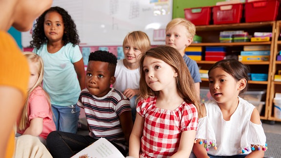 KInder hören beim Vorlesen zu.