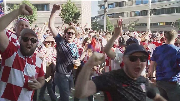 Fans der kroatischen Nationalmannschaft laufen über eine Straße.